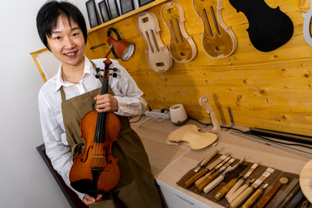 young Chinese violin maker at work in her workshopの写真素材