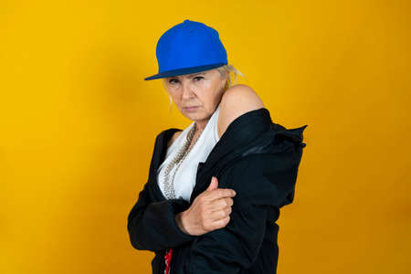 Funny portrait of mature woman. Lady having fun dressed as an angry rapper. Mature woman on colored...