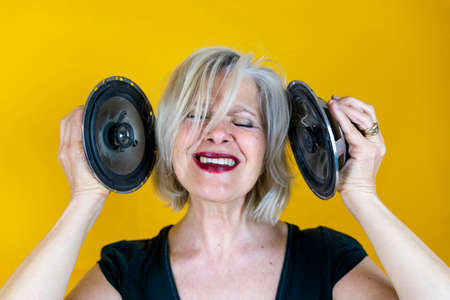 Funny portrait of mature woman. Beautiful lady having fun listening loud music. Mature woman on...