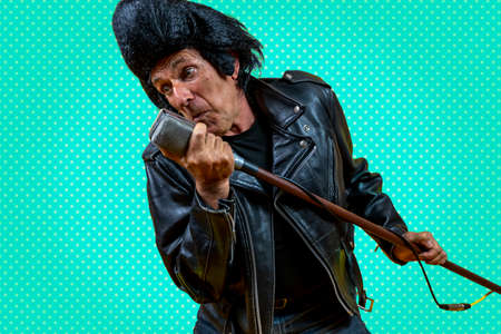 Funny portrait of mature rocker. An old singer dressed in rockabilly style in action. Mature man on...