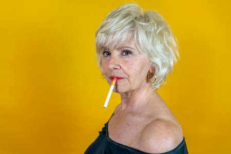 Funny portrait of mature woman. Beautiful lady is wearing 50s style leather clothes smoking a...