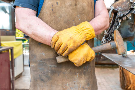 detail of the hands of a blacksmith. Iron worker holds a hammerの写真素材