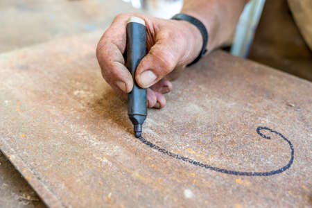 close-up of hand is writing with a black marker on a metal panelの写真素材