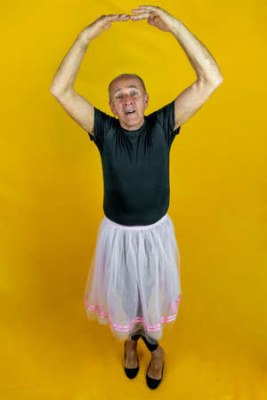 funny portrait of male ballet dancer. A mature ballet dancer dressed in tutu dancing clumsily on colorful backgroundの写真素材