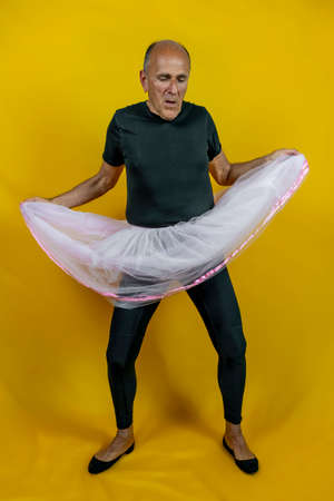 funny portrait of male ballet dancer. A mature ballet dancer dressed in tutu dancing clumsily on colorful backgroundの写真素材