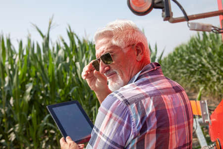 modern technological farmer while checking the growth data of corn on the tablet of his cultivated fields. concept of sustainable exploitation of natural resources.の写真素材