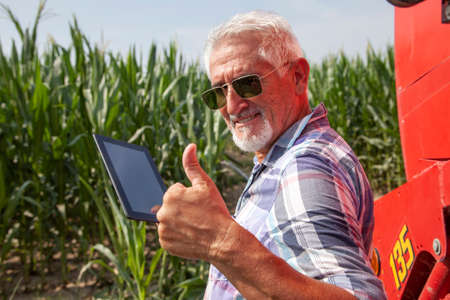 modern technological farmer while checking the growth data of corn on the tablet of his cultivated fields. concept of sustainable exploitation of natural resources.の写真素材