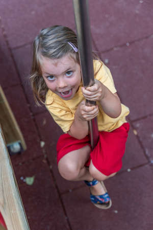 cute little girl have fun climbing a wooden structure in a playground