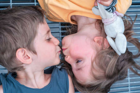 portrait of twins boys and girls are kissing lying on a metal grateの写真素材