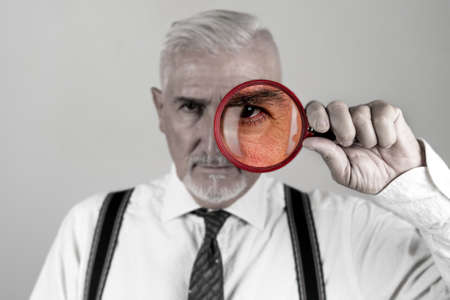 portrait of investigator while looking with magnifying glass isolated on gray backgroundの写真素材