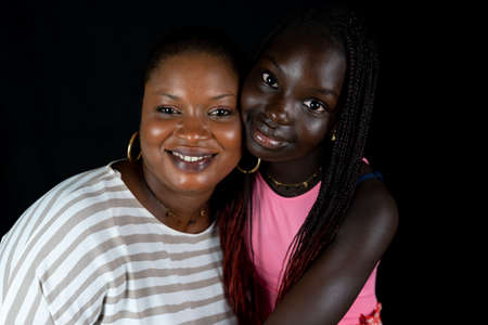 African american mother and daughter smiling happy hugging on black backgroundの写真素材
