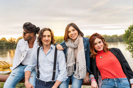 group of best friend have fun together in front of a big river in autumn at sunset - Happy friendship conceptの写真素材