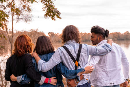 group of best friend have fun together in front of a big river in autumn at sunset - Happy friendship conceptの写真素材
