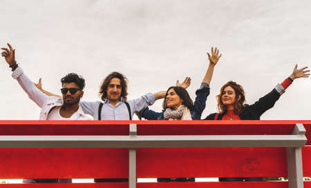 group of best friends screaming to the sky from a big red benchの写真素材