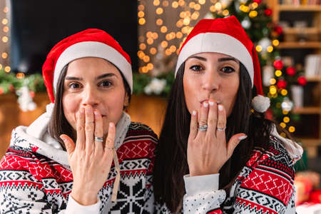 cute young women dressed in red hat and christmas sweatshirt blowing a kiss - Concept of happiness...