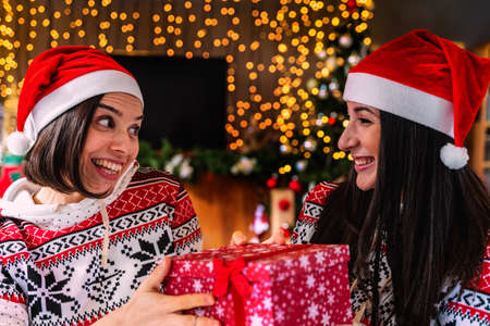 cute young women with red cap are surprised to receive a christmas gift package - Concept of happiness during the holiday seasonの写真素材