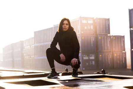 young female runner takes a break on a freight train in the commercial port in the morning - Health and wellness conceptの写真素材