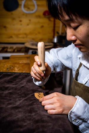 young Chinese woman violin maker signs the jumper of her violin with fire with her name in the...