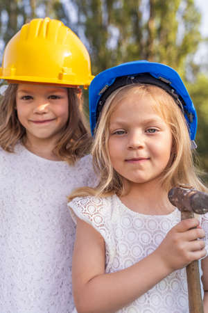 two little girls sisters pitching the tent at the campsite wearing protective helmets - fun conceptの写真素材