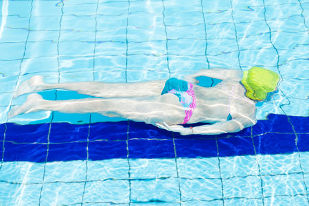 young girl having fun swimming underwater in the poolの写真素材