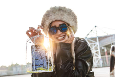 young pretty woman with russian cap showing a smartphone inside a metal cage. concept of technology...
