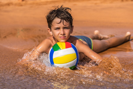 young boy playing with a soccer ball on the beach by the sea - summer vacation conceptの写真素材