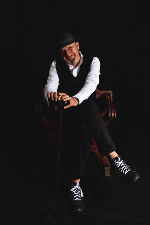 portrait of white bearded hipster man sitting in a photo studio on a black background