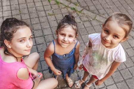 three smiling little girls look into the camera outdoorsの写真素材
