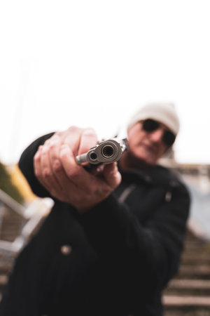 mature man rap singer posing in the street with a gun in his hand in the suburbs of a big city