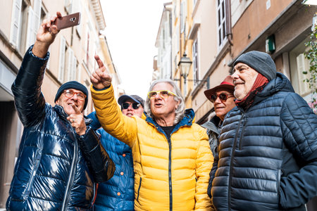 group of happy retired mature men taking a selfie with smart phone on the street in winter