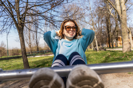 portrait of young woman doing abdominal muscles workout on a bench outdoors - wellness concept