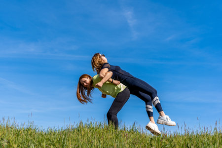 couple of pretty athletic women doing gymnastics exercises outdoors - wellness concept