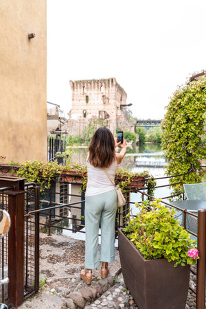 beautiful woman takes a photo of the landscape with the smart phone from a lakeside terrace - travel and vacation conceptの写真素材