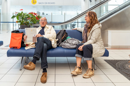 beautiful retired couple sitting in waiting room before embarking on cruise - travel and vacation conceptの写真素材