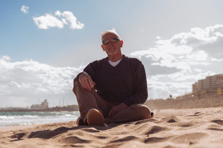 handsome middle aged man relaxing sitting on a beach in Tarragona, spain - Tourism and holidays conceptの写真素材