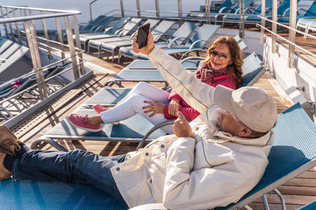 beautiful happy middle aged couple taking a selfie with smartphone on a cruise ship - travel and...