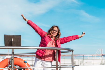 beautiful happy middle aged woman having fun on the deck of a cruise ship - travel and vacation conceptの写真素材