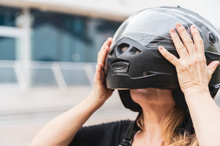 portrait of middle aged blonde female biker putting black helmet on headの写真素材