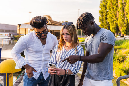 small group of multiethnic friends having fun with smartphone - summer vacation concept on a boat sailing on a riverの写真素材