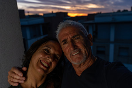 beautiful romantic middle aged couple taking a selfie on the outdoor terrace at sunset