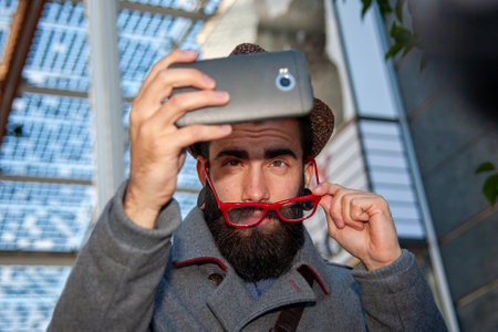young hipster businessman taking a selfie with smartphone outdoors in a European capital