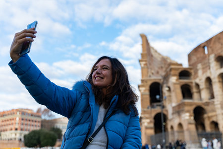 happy middle aged woman on vacation taking a selfie in front of coliseum amphitheater in rome - fun and vacation concept.の写真素材
