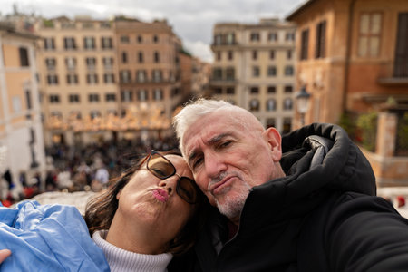 happy middle aged couple of tourists on vacation taking a selfie in front of the famous trinitÃ ...