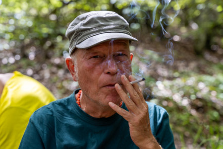 portrait of mature man in mountain woods dressed in hat and sports clothes and backpack