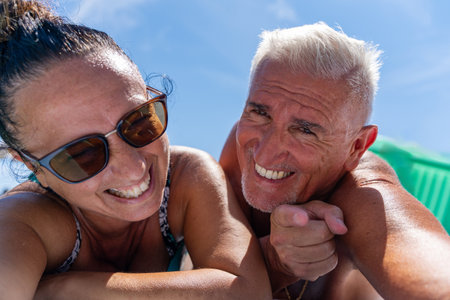 beautiful middle aged couple happy and smiling taking a selfie on summer vacation on the lakeの写真素材