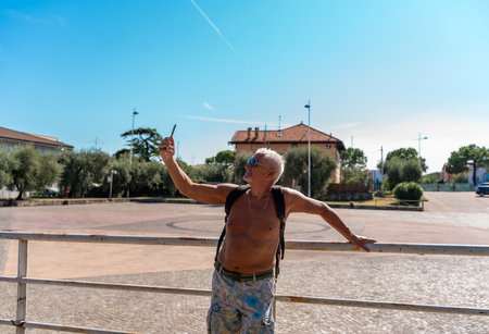 a middle aged man with white hair and goatee happy and smiling taking a selfie on summer vacationの写真素材