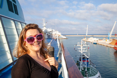 beautiful blonde woman enjoying the trip on a cruise ship looking at the seaの写真素材