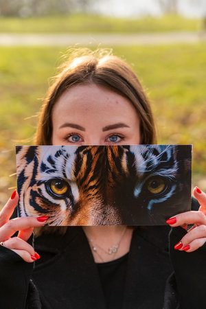 portrait of young woman having fun showing a fantasy image partially covering their face in a public park in winterの写真素材