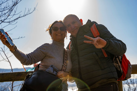 beautiful middle-aged couple in love taking a selfie while trekking in the hillsの写真素材