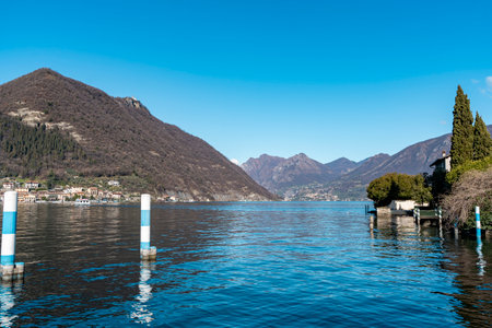 beautiful view of the pier of a small tourist port on the blue waters of Lake Iseo with the mountains in the backgroundの写真素材